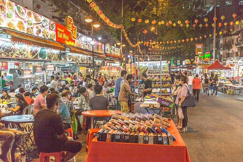 Food stalls, outdoor tables and lanterns along Jalan Alor at night.
