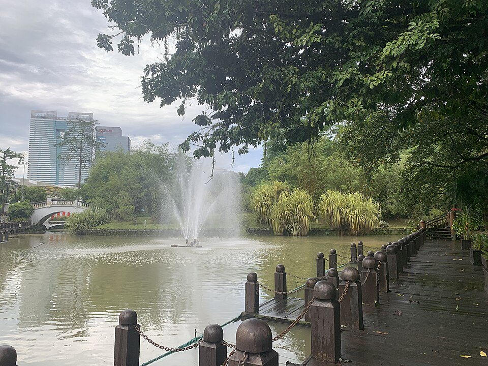 A lakeside path and fountain in Perdana Botanical Gardens.